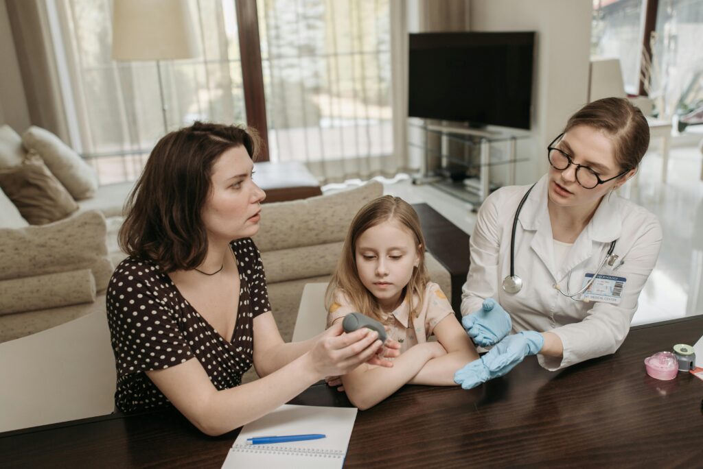 pexels photo 7653310 7653310 Doctor consults mother and daughter at home, discussing medical device in the living room.